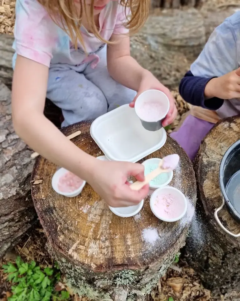 Children mixing the Wicked Enchantment magic potion outdoors using pastel pink and green powders, creating a fizzing potion on a tree stump during imaginative sensory play – Sparkle & Spell Co. Magic Potions NZ